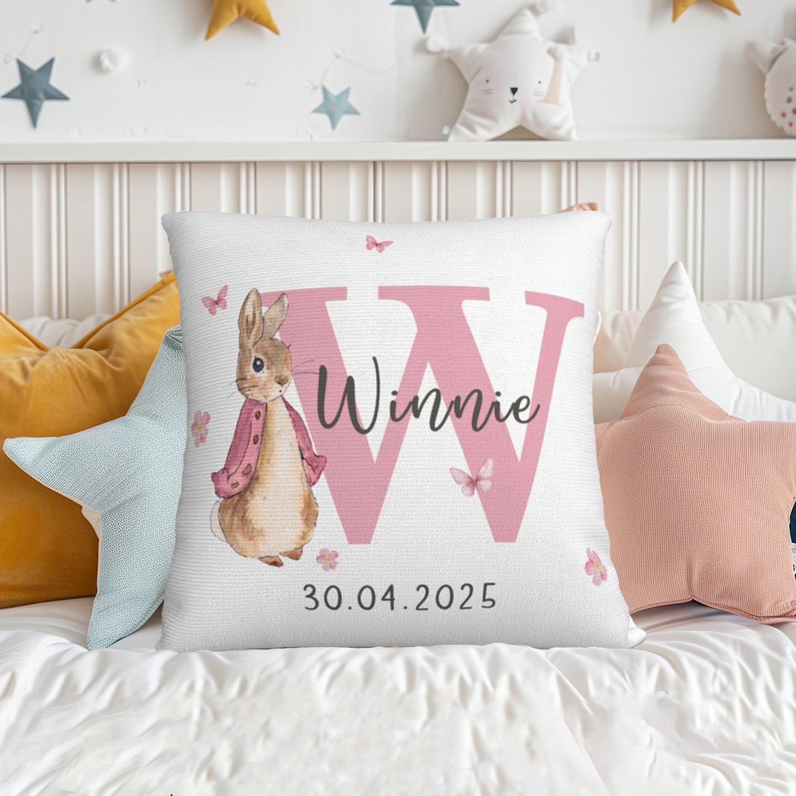 Personalized Peter Rabbit bunny pillow with pink lettering and custom name on bed, sweet nursery decor
